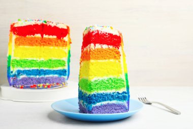Lezzetli bir parça gökkuşağı pastası beyaz masada, yakın plan.