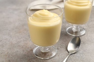 Gri masada servis edilen lezzetli vanilyalı puding, yakın plan.