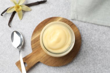 Lezzetli vanilyalı puding, kapsüller ve çiçek gri masada, düz uzanmış