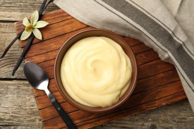 Lezzetli vanilyalı puding, kapsüller ve çiçek ahşap masada, düz uzanmış