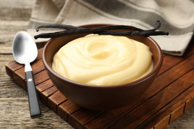 Tahta masada servis edilen lezzetli vanilyalı puding ve kapsüller.