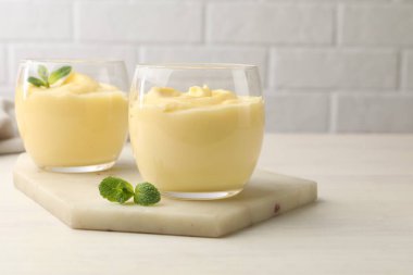 Beyaz ahşap masada naneli vanilyalı puding.