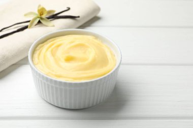 Lezzetli vanilyalı puding ve kapsüller beyaz ahşap masada, yakın plan. Metin için boşluk