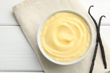 Lezzetli vanilyalı puding ve beyaz ahşap masadaki kapsüller.