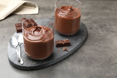 Lezzetli puding ve gri masada çikolata parçaları.