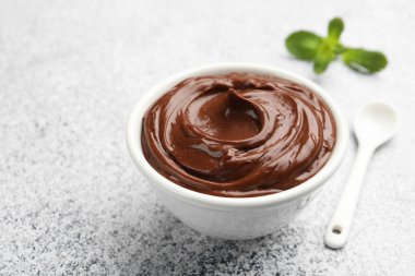 Kasede lezzetli çikolatalı puding ve açık gri desenli masada kaşık, yakın plan. Metin için boşluk