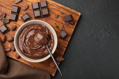 Kasede lezzetli puding, çikolata parçaları ve siyah masada kakao çekirdeği, düz yatak. Metin için boşluk