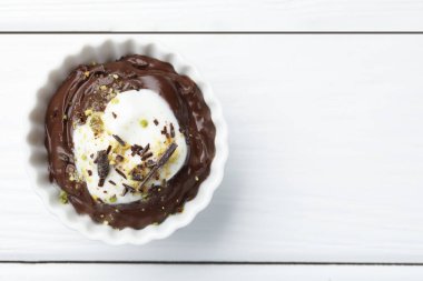 Lezzetli çikolatalı puding, beyaz ahşap masada krema kasesi, üst manzara. Metin için boşluk