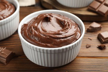 Tabaklardaki lezzetli pudingler ve ahşap masadaki çikolata parçaları, yakın plan.