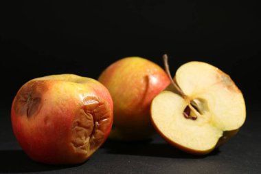 Siyah arkaplanda kesilmiş çürük elmalar, yakın plan.