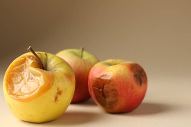 Bej arka planda üç çürük elma, yakın plan.