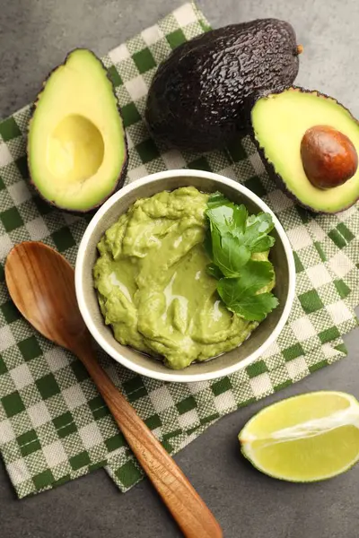 Lezzetli avokado sosu, maydanoz ve meyveler gri masada, düz yerde.