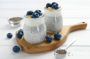 Chia tohumlu lezzetli puding, yoğurt, yaban mersini ve granola beyaz ahşap masada, yakın plan. Süper yemek.