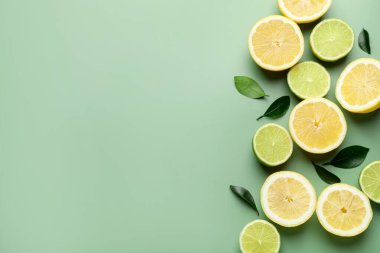 Soluk yeşil arka planda limon ve limon dilimleri, düz. Metin için boşluk