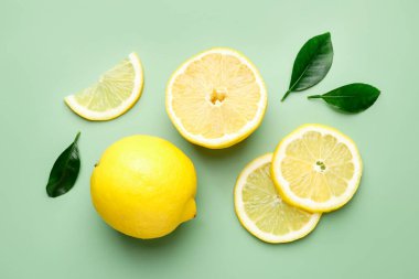 Taze limon ve yapraklar soluk yeşil arka planda, düz yatıyordu.