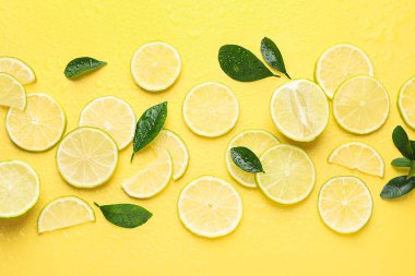 Taze limon dilimleri ve sarı arka planda yeşil yapraklar.