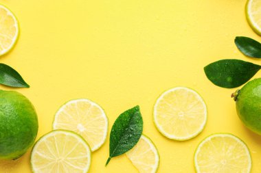 Taze limon ve yeşil yapraklar sarı arka planda, düz yerde. Metin için boşluk