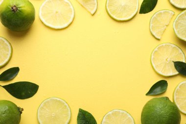 Taze limon ve yeşil yaprakların çerçevesi sarı arka planda, düz yerde. Metin için boşluk