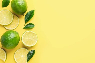 Taze limon ve yeşil yapraklar sarı arka planda, düz yerde. Metin için boşluk