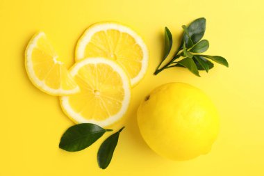 Taze limon ve yeşil yapraklar sarı arka planda, düz yatıyordu.