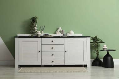 İçerideki yeşil duvarın yanında farklı dekorları olan bir dolap. İç tasarım