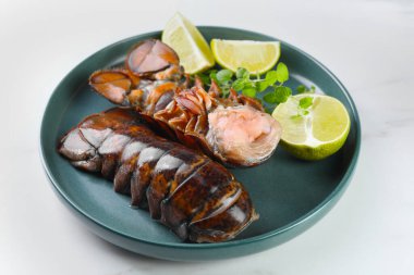 Çiğ ıstakoz kuyruğu, kireç ve mikro yeşiller beyaz masada, yakın plan.