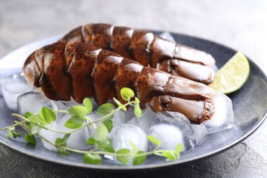 Çiğ ıstakoz kuyruğu, mikro yeşillikler, masada limon ve buz, yakın plan.