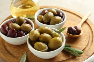 Lezzetli marine edilmiş zeytinler kaseler, kaşık, yağ ve yeşil yapraklar masada, yakın çekim