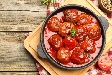 Ahşap masadaki fırın kabında domates soslu leziz köfteler. Metin için boşluk