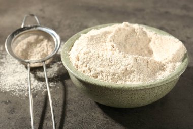 Kahverengi pirinç unu ve elek gri masada, yakın plan.