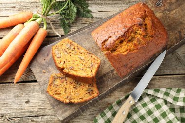 Ev yapımı havuçlu kek, fındıklı, bıçaklı ve sebzeli, ahşap masada, düz uzanmış.