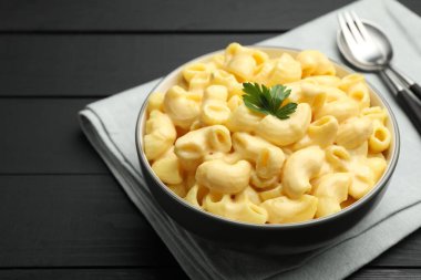 Siyah ahşap masada servis edilen maydanozlu lezzetli makarna ve peynir.