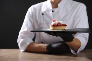 Ahşap masada nefis tartlı şekerci, siyah arka planda, yakın plan.