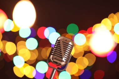 Karanlık arka planda bulanık ışıkları olan klasik mikrofon, mesaj için yer. Müzik ekipmanları