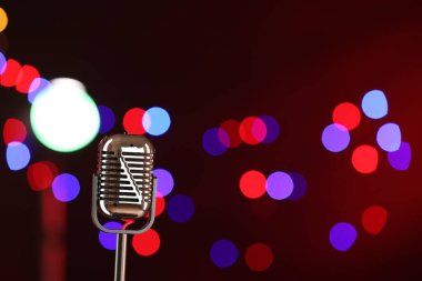 Koyu kırmızı arka planda, bulanık ışıkları olan klasik mikrofon, mesaj için yer. Müzik ekipmanları