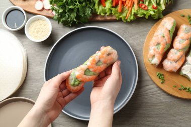 Gri ahşap masada nefis börek yapan bir kadın.