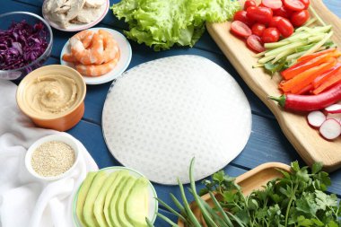 Pirinç kağıt çarşaflar ve mavi ahşap masa üzerindeki farklı malzemeler.