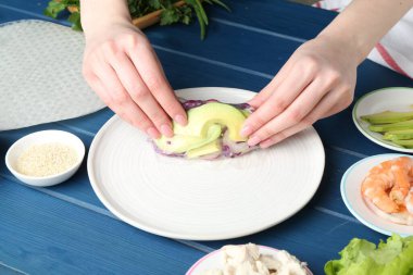 Mavi ahşap masada nefis börek yapan bir kadın, yakın plan.