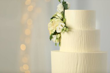 Bulanık arkaplanda çiçek dekoru olan nefis düğün pastası, mesaj için yer. Bokeh etkisi