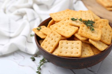 Lezzetli tuzlu krakerler ve kekik beyaz masada, yakın plan.