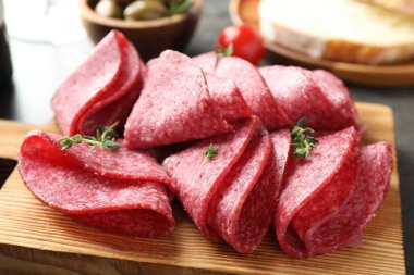 Gri masada servis edilen lezzetli sosis dilimleri, yakın plan.