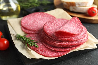 Lezzetli füme sosis ve biberiye dilimleri siyah masada, yakın plan.