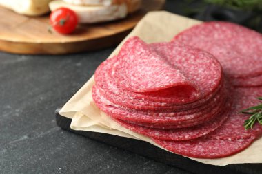 Lezzetli füme sosis ve biberiye dilimleri siyah masada, yakın plan.