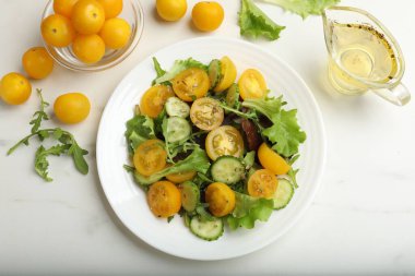 Beyaz masada sarı domatesli taze salata.