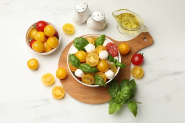 Taze salata, sarı domatesler, fesleğen ve mozzarella peyniri beyaz mermer masa, düz yatıyordu.