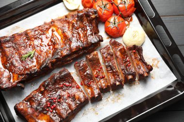 Lezzetli kaburgalar, fırında soğan ve kurutulmuş domatesler, gri ahşap masa, üst manzara.