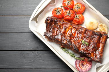 Lezzetli kaburgalar, biberiye, fırında soğan ve gri ahşap masada kurutulmuş domatesler, üst manzara. Metin için boşluk