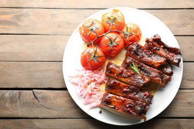 Lezzetli pirzolalar, soğan ve kurutulmuş domatesler ahşap masa, üst manzara. Metin için boşluk