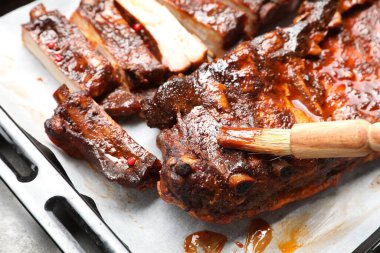 Gri masadaki nefis kaburgaların üzerine fırçayla sos serpiştiriyorum.