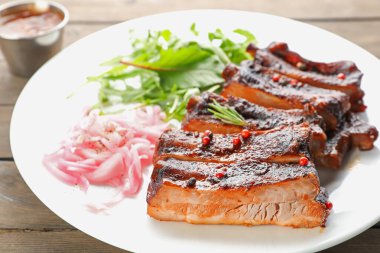 Lezzetli domuz pirzolası, roka ve soğan ahşap masada, yakın plan.